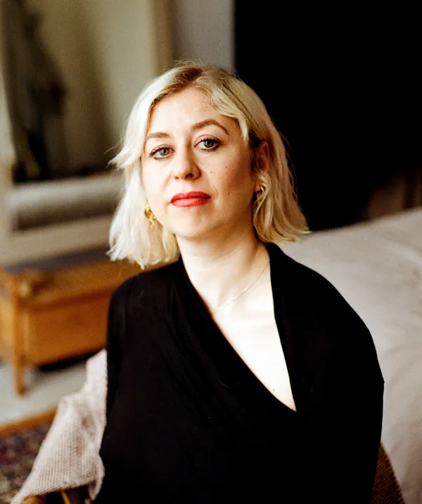 A white woman with a bob or pale blond hair, wearing a black evening dress.