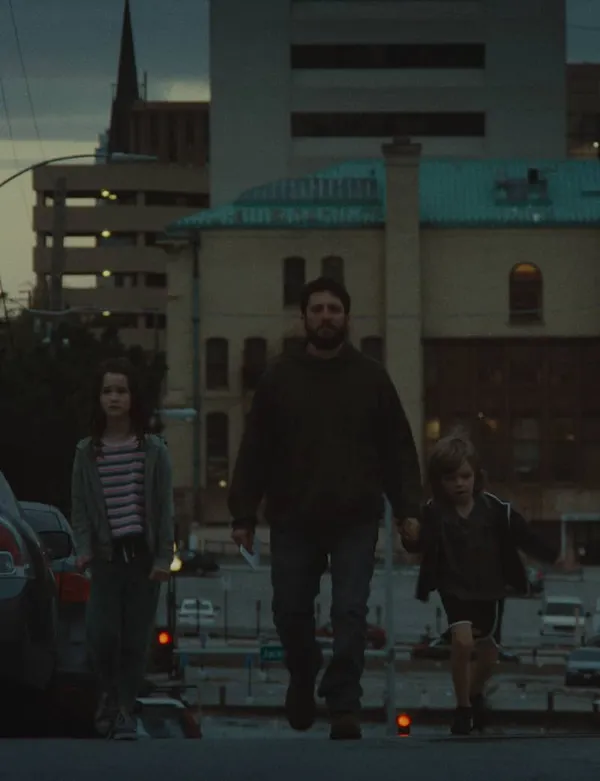 A dad walks hand in hand with his daughter and son up a street