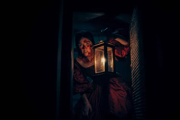 A still from the film Mārama. A young Māori woman in a red dress peers into a secret passage, clutching a lantern.