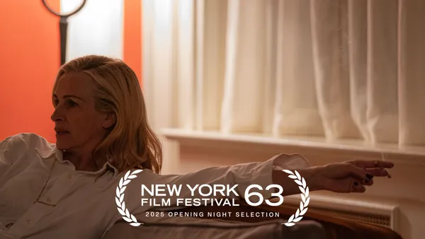 A still from the film After The Hunt. A white woman sits at one end of a sofa in a room whose curtains are drawn.