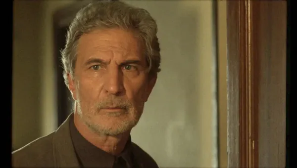 A still from the film Weightless. A grey-haired older white man with a short beard.