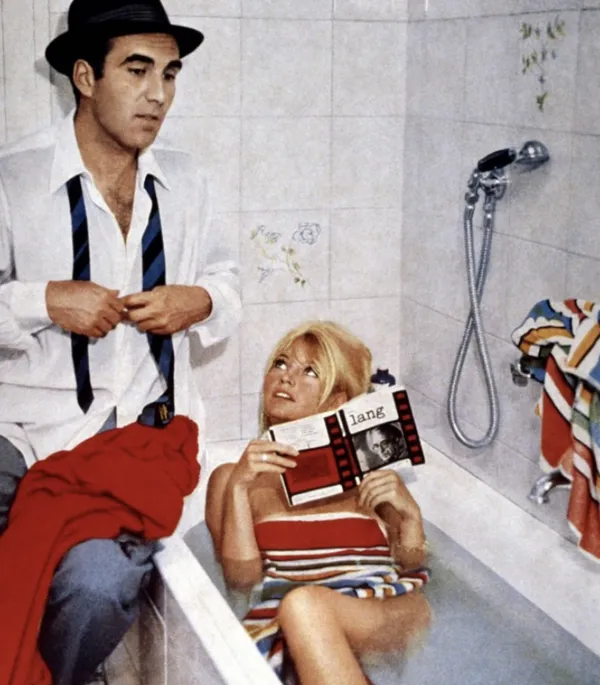 Bardot in a bath with a book, a man is beside her with an untied tie buttoning his shirt