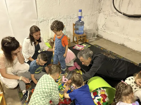 Bernard-Henri Lévy playing with children during an air-raid