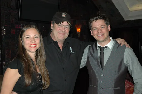 Claire Bueno, Dan Aykroyd and Anthony Bueno. A middle-aged white man wearing a black shirt and baseball cap stands with his arms around a younger white woman and white man. All three are smiling.
