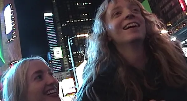 A still from the film Castration Movie Part II. A short blond woman with light blond hair walks through New York City at night beside a taller blond.