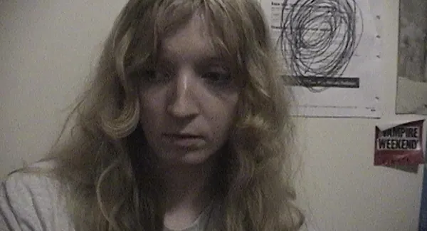 A still from the film Castration Movie Part II. A close-up of a shy-looking white person with long blond hair.