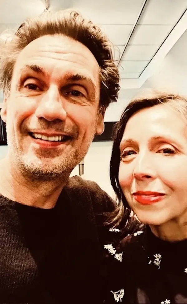 A smiling middle-aged white man and woman, captured by a phone camera.
