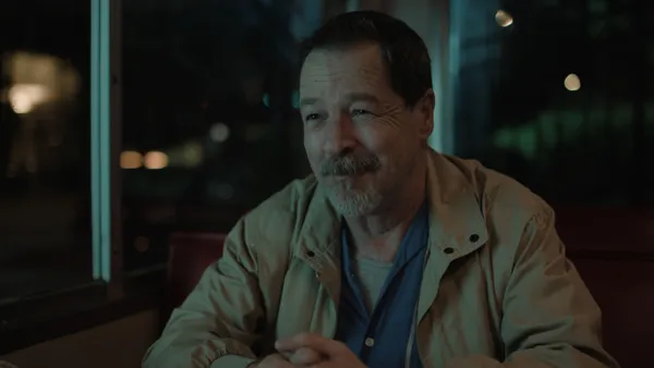 A still from the film Bob Trevino Likes It. A middle aged white man sits in a café at night.