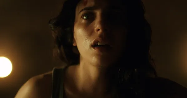 A still from the film Hellcat. A close-up of the face of a light-skinned, dark-haired, sweaty, anxious and determined young woman.