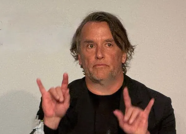 Richard Linklater makes devil's horn signs with his hands at Cannes press conference