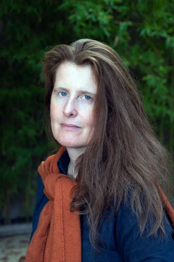 Portrait shot of Isabelle Ingold, she has shoulder length brown straight hair and is wearing a rust coloured scarf