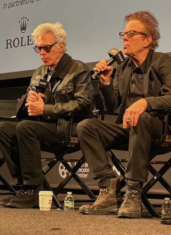 Jim Jarmusch and Tom Waits. Two older white men sit on folding chairs in front of a cinema screen holding microphones marked NYFF.