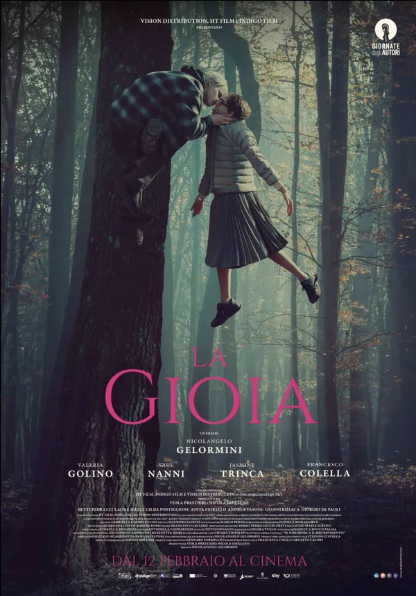 A poster for the film La Gioia. A young blond man crouches on a tree branch in a forest, leaning over to kiss a dark-haired, bespectacled middle-aged white woman who seems to be floatinng in the air beside him.