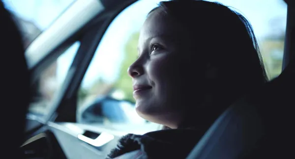 A still from the film What Marielle Knows. A white girl sits in the front passenger seat of a car.