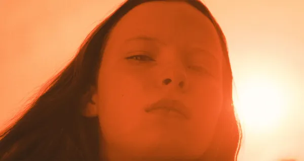 A still from the film What Marielle Knows. The blurry face of a white girl in a haze of warm light.