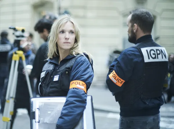 A still from the film Case 137. Part of a group of police officers in an urban street, a blond white woman looks around with a worried expression.