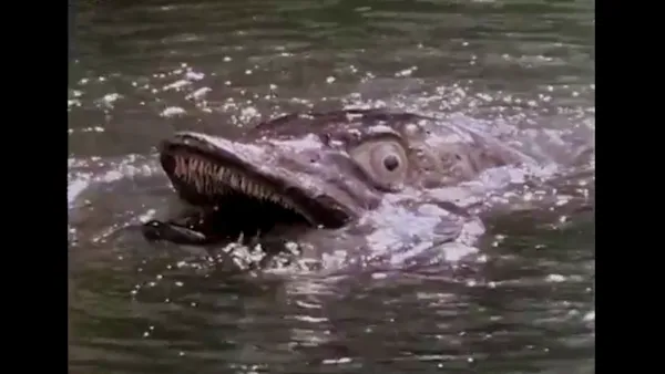 A still from The Pike. A giant model pike (of the fishy variety) immersed in murky water.