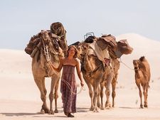 Mia Wasikowska as Robyn Davidson in the company of three adult camels and a calf named Goliath.