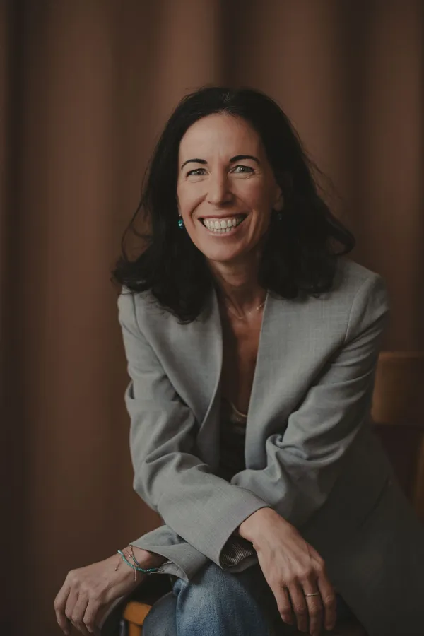 Portrait photo of Natalie Halla, she has shoulder length brown hair and is smiling. She is wearing a grey jacket