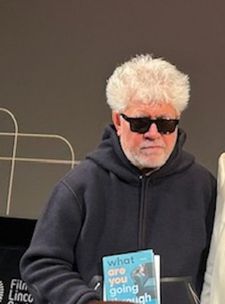 Pedro Almodóvar holding up What Are You Going Through by Sigrid Nunez