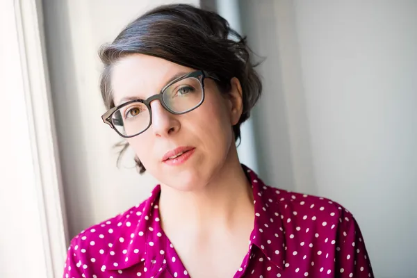 The filmmaker Petra Volpe. A bespectacled white woman with greying brown hair neatly tied back, wearing a pink top with small white polka dots on it.