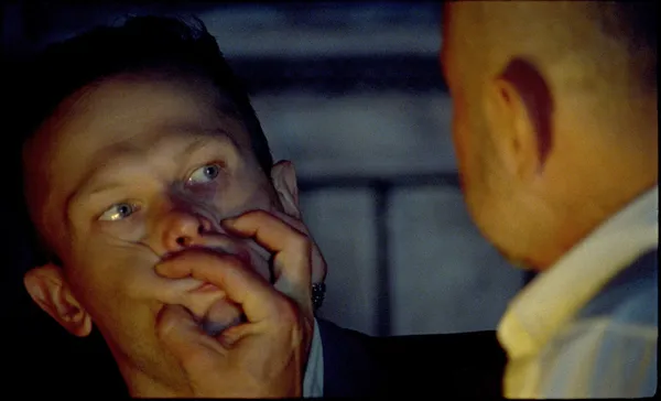 A white man squashes another white man's face with his hands.
