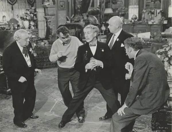 A black and white still from the film Ball Of Fire. A group of older white men in suits try to work out how to dance.