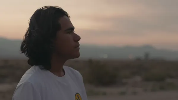 A still from the film Remaining Native. A young Paiute man looks out across the land where he runs.