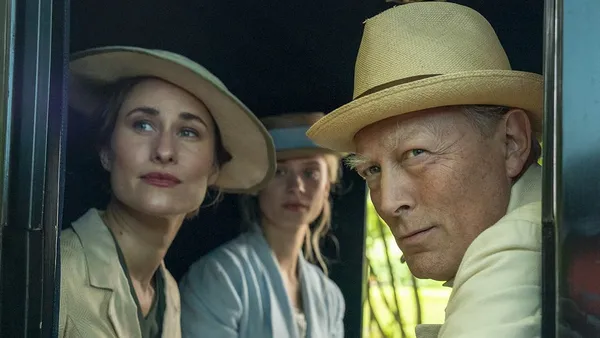A still from the film The Kiss. An older white man wearing a hat, a middle aged white woman and a young white woman look out through a carriage window.