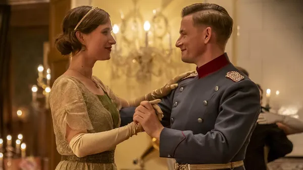 A still from the film The Kiss. A brown-haired young white woman engages in a formal dance with a soldier.