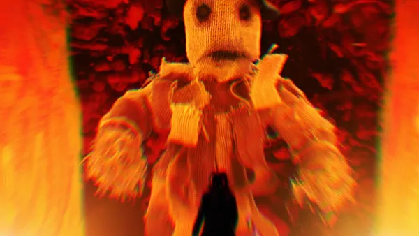 A still from the film The People's Joker. A straw scarecrow looms large against a fiery background.