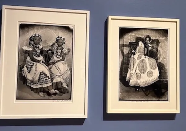 Two large black and white photo graphic prints of African women, mounted on a blue wall.