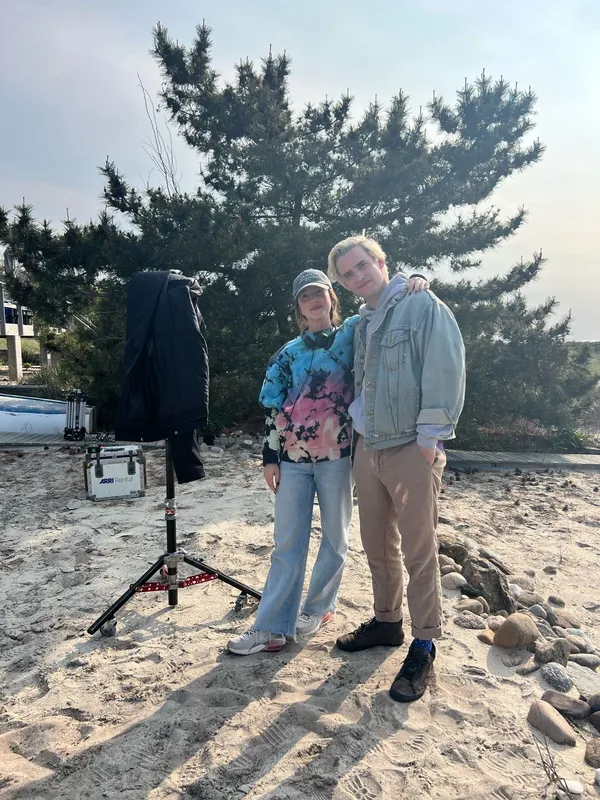 The film directors Sofia Camargo and Joseph Longo. A white woman and a white man stand on sand with a sprawling fir tree behind them.