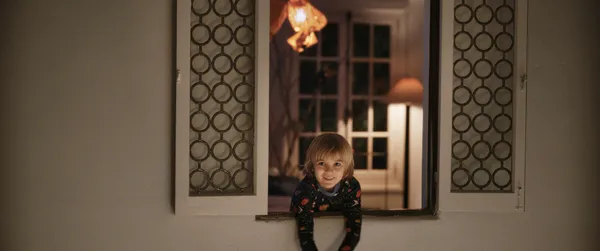 A still from the film The Uninvited. A child wearing a galaxy-themed top leans out of a window at night.