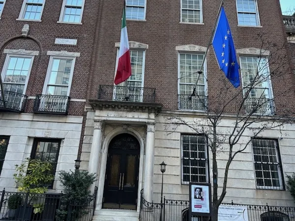 A Geogian-era urban building with a white-painted lower storey, sporting Italian and EU flags.