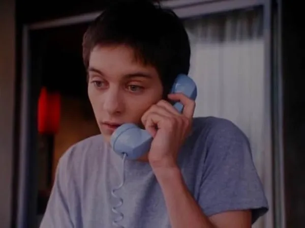 A still from the film Duke Of Groove. A white teenage boy wearing a grey t-shirt speaks into the receiver of a rotary dial phone.