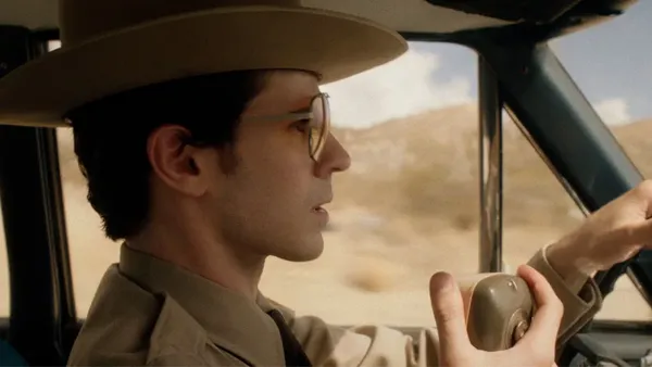 A still from the film The Last Stop In Yuma County. A teenager in a sheriff's department uniform speaks into a radio whilst driving a car.