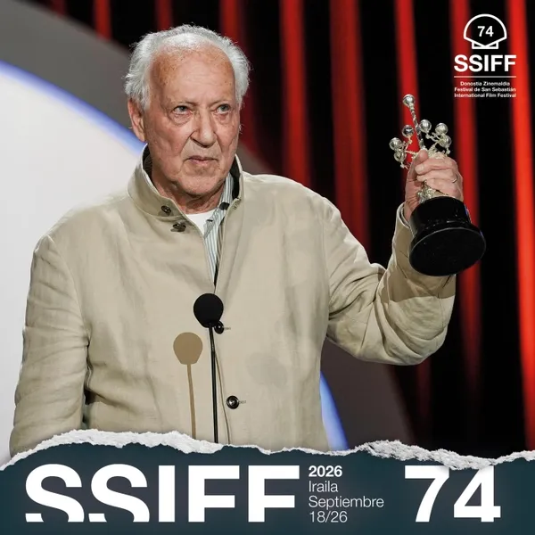 The filmmaker Werner Herzog, a white man in his eighties, holds up a Donostia award