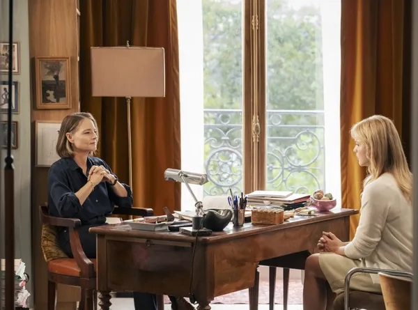 Two women sit chatting at opposite sides of a desk