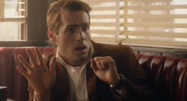 A still from the film The Last Stop In Yuma County. A startled looking white man in a brown jacket sits in a booth in a café where golden sunlight pokes through the Venetian blinds.
