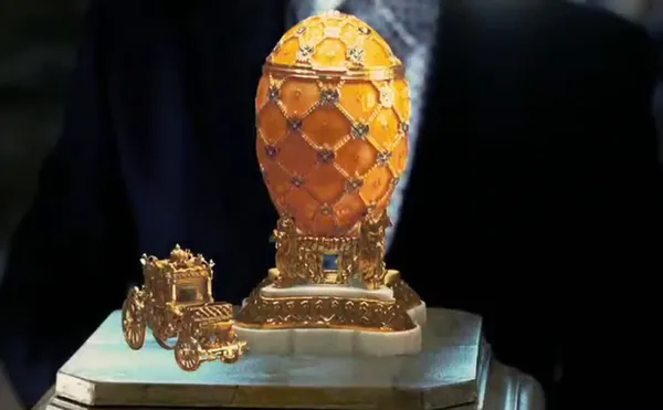 A still from the film Ocean’s 12. A man in a dark suit presents a Fabergé egg.
