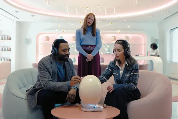 A still from the film The Pod Generation. Three people gather around a giant egg.